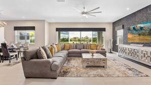 A spacious living room with a large sectional sofa, a coffee table, and a dining area with a table and chairs.