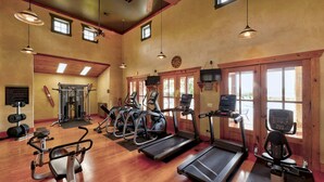 Un gimnasio con cintas de correr, elípticas y equipo de levantamiento de pesas.