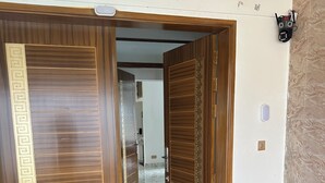 A wooden door with a geometric pattern, a black mat at the entrance, and a wall-mounted light fixture. - Specious Wonderful 2 AC & 2 NON AC bedroom apartment in West Khulshi,Chittagong (Chittagong)