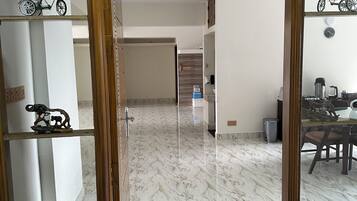 A room with a marble floor, a wooden-framed mirror, and a dining area with a table and chairs.