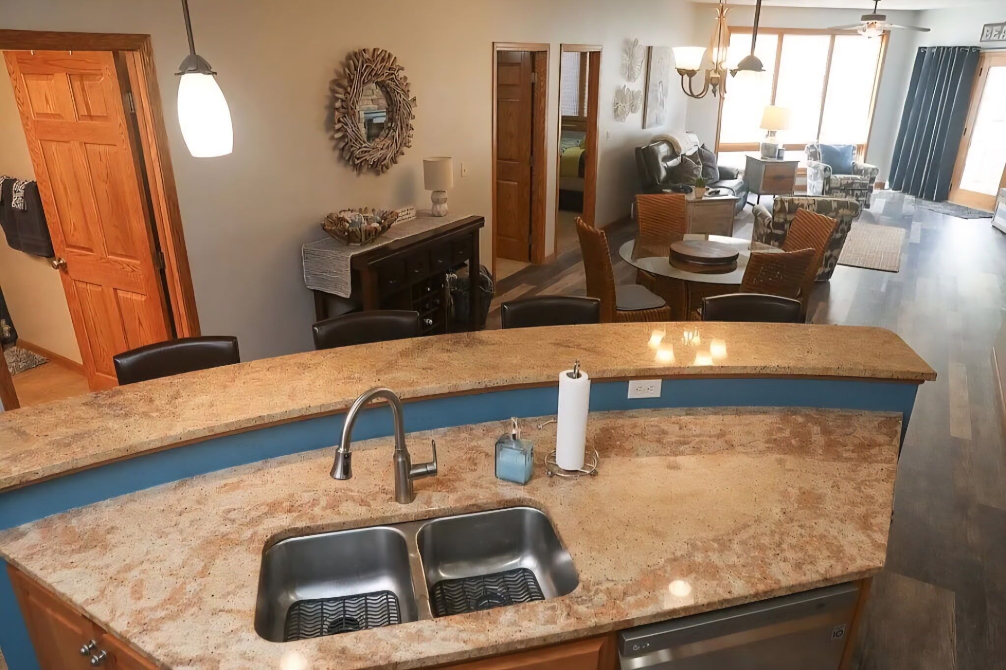 A kitchen with granite countertops, a double sink, and a dining area with a round table and chairs.