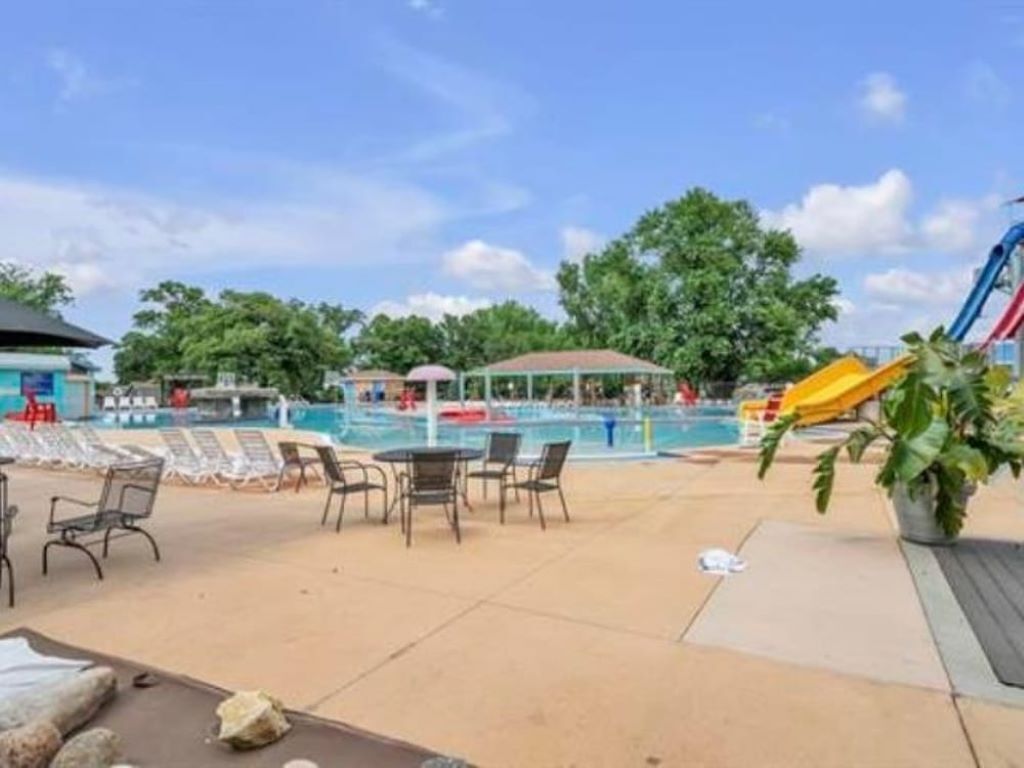 A pool area with lounge chairs, a covered seating area, and a slide.