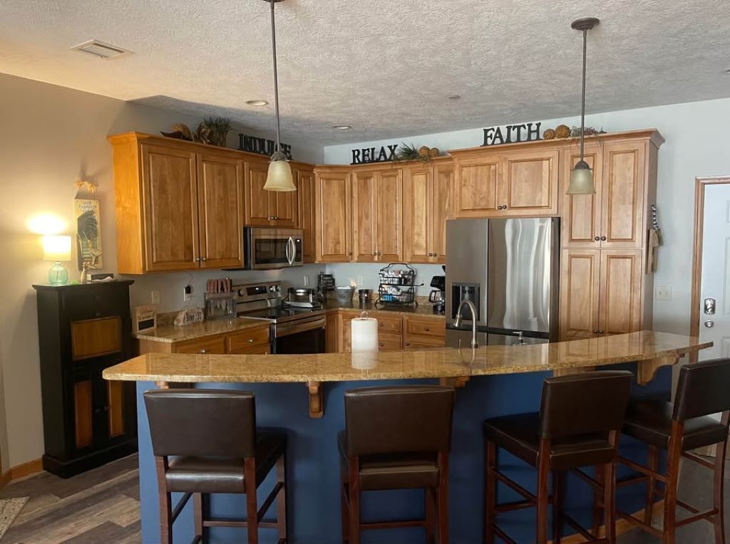 Una cocina con armarios de madera, encimera de granito y una isla central con taburetes de bar.