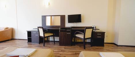 A hotel room with a bed, a desk, a chair, a television, and a mirror.