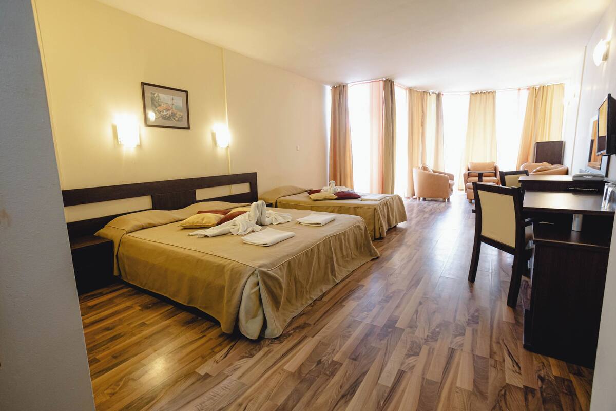 A hotel room with two beds, a desk, and a chair.