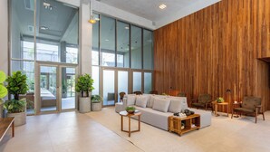 A spacious living area with a large sofa, wooden side tables, and potted plants. - Luxo em rua icônica no Itaim Bibi (Sao Paulo)