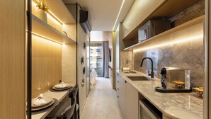 A narrow kitchen with a marble countertop, a built-in oven, and a sink. - Luxo em rua icônica no Itaim Bibi (Sao Paulo)