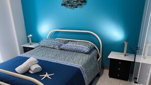 Quarto moderno com cama, mesa de cabeceira, cômoda e uma obra de arte na parede.