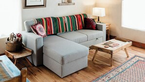 A cozy living room with a gray sofa, wooden coffee table, and a patterned rug.