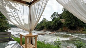 A wooden deck with a table and bench overlooking a river. - Yeşil Düş Bungalov (Findikli)