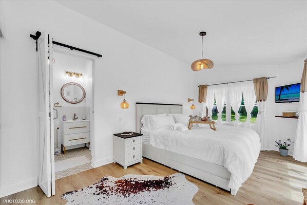 Un dormitorio moderno con una cama grande, mesitas de noche, un armario y un televisor.
