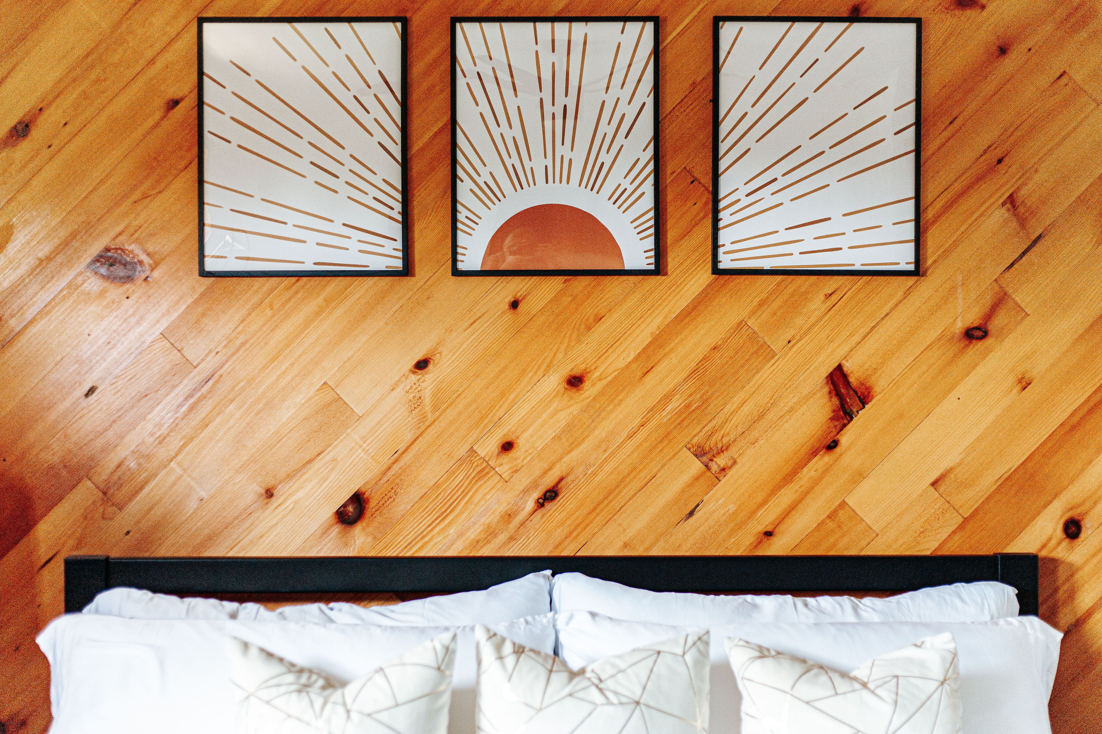 A wooden floor with three framed artworks depicting sun rays and a crescent moon.