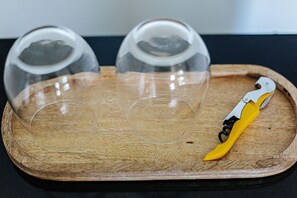 A wooden tray with three clear glass domes and a yellow and white bottle opener.