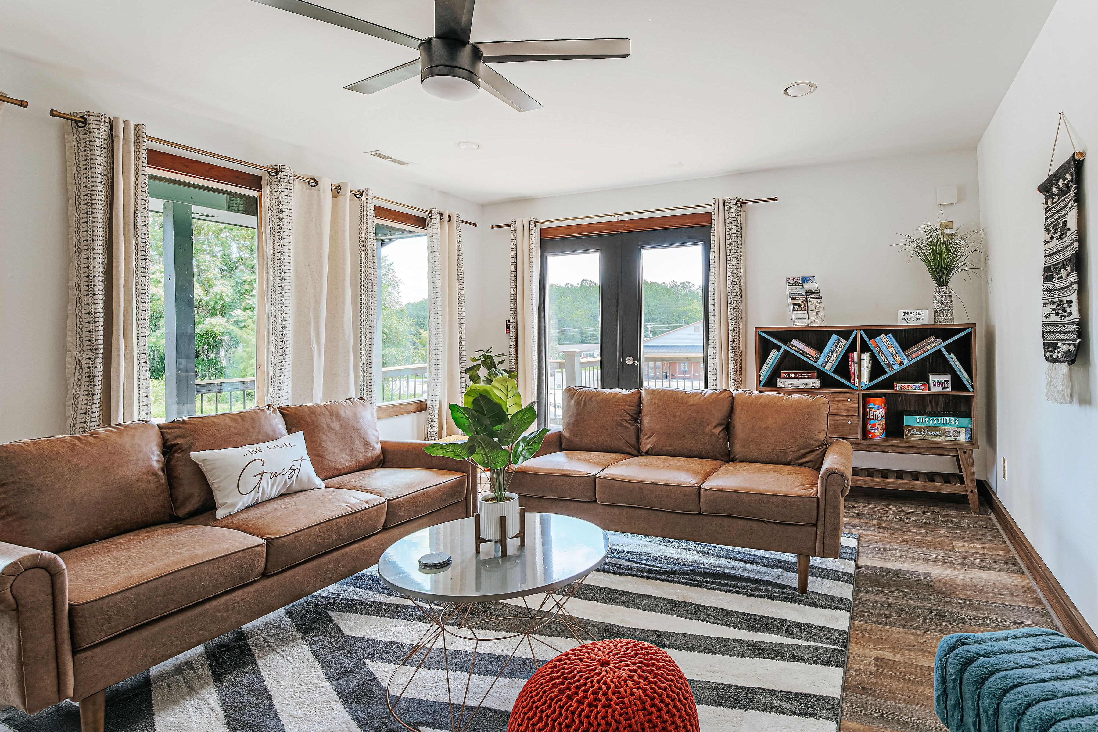 A modern living room with a brown leather sofa, a coffee table, and a bookshelf.
