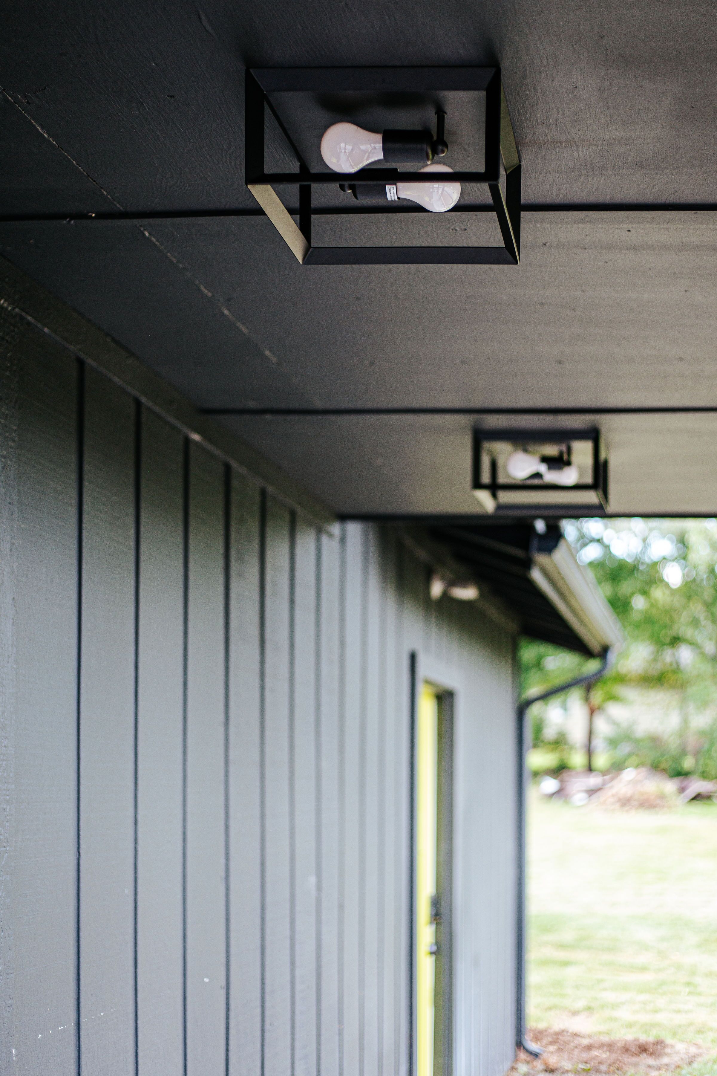 A building exterior with a dark gray siding and a yellow door.