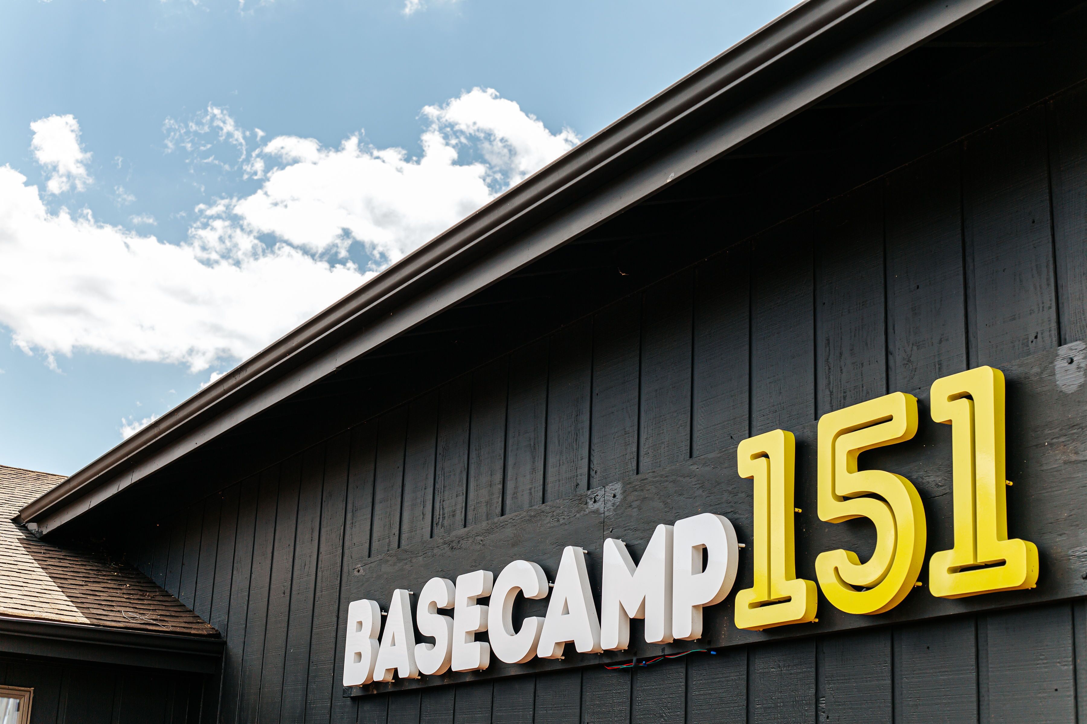 A building with a sign that reads "BASECAMP 151" on a dark wooden facade.
