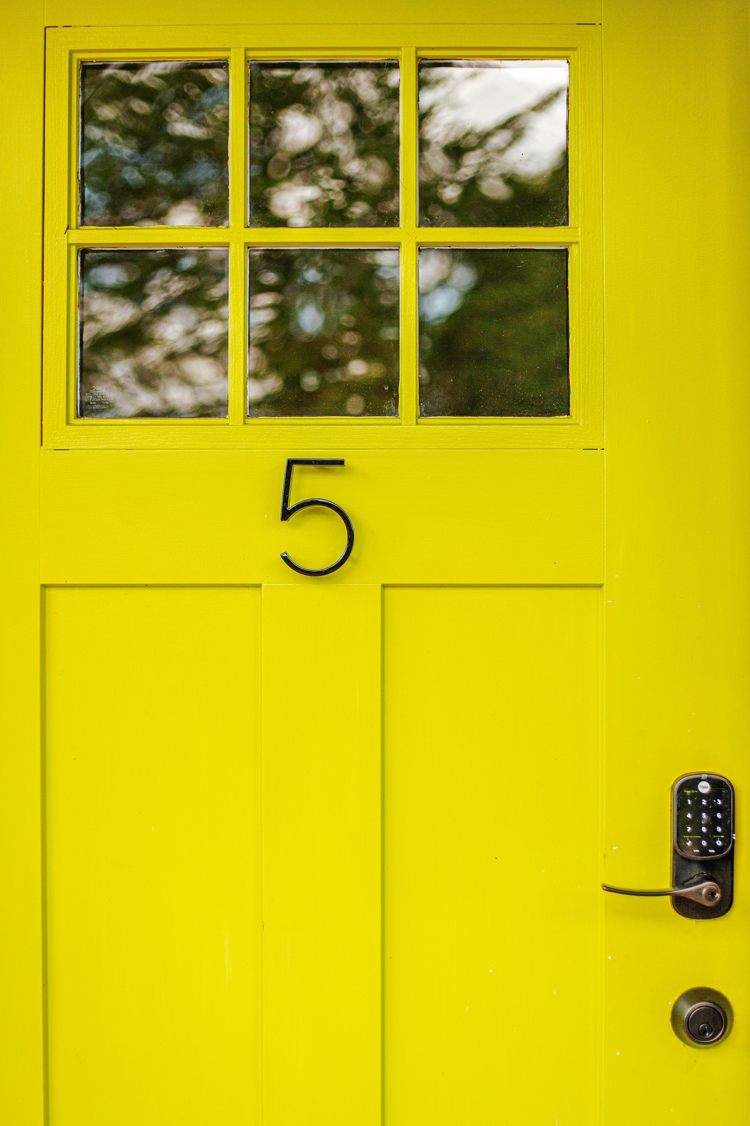 A yellow door with a window and the number 5.