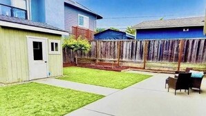 Un patio trasero con terraza, cerca de madera y un pequeño jardín.