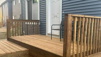 Une terrasse en bois menant à une maison avec une porte blanche et une pancarte indiquant «
Bienvenue
».