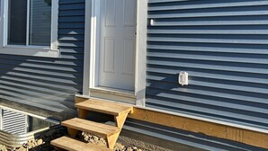 A house with a front door, a window, and a small wooden bench outside. - 1BR suite, fully private, no shared space, 20 mins from airport. (Edmonton)