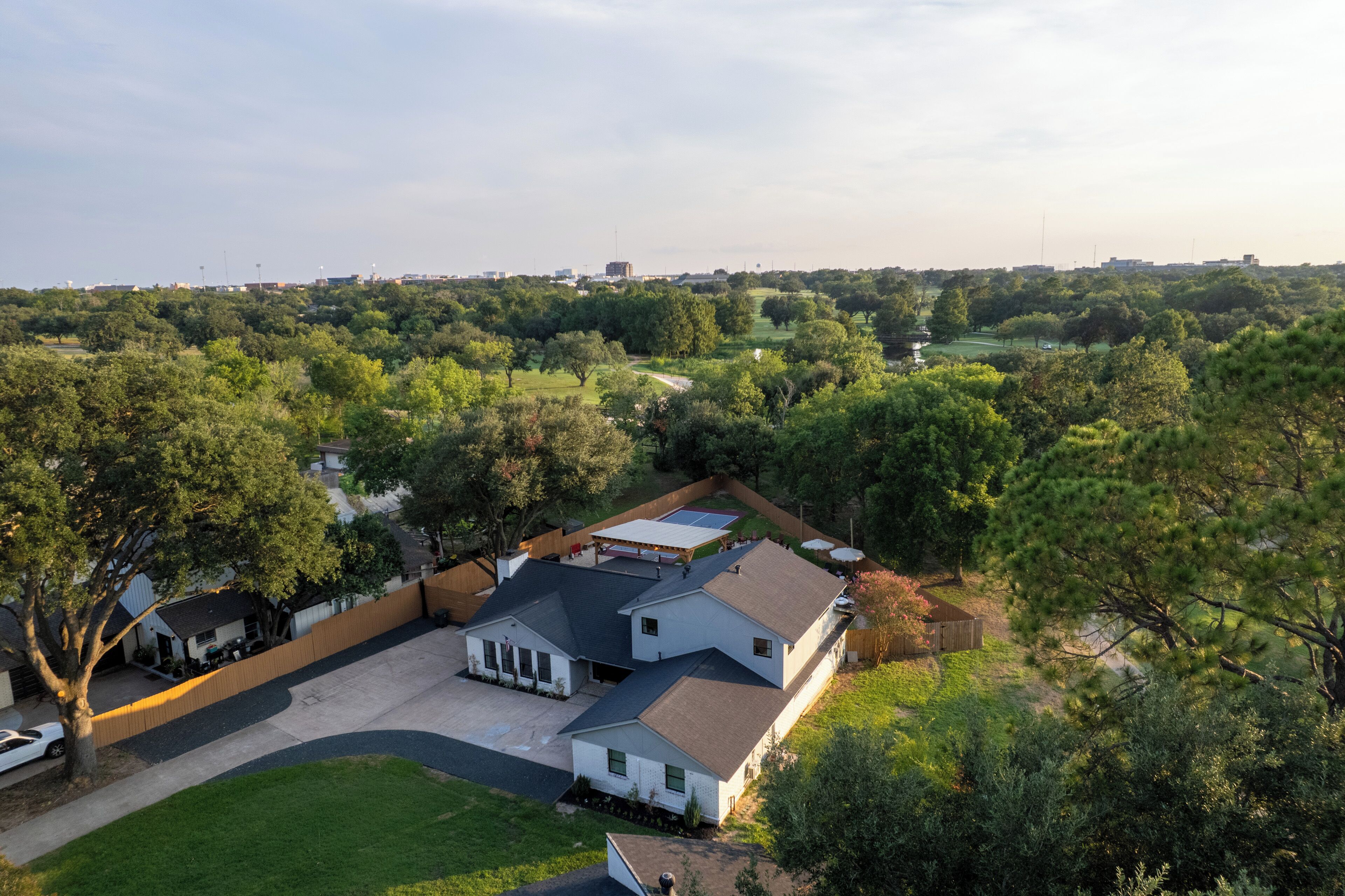 A residential property with a large house, a covered patio, and a fenced yard.