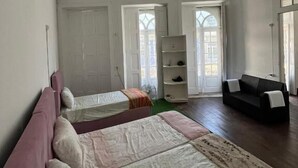 A room with two beds, a sofa, and a fan. - Casa Augusta 2 (Braga)