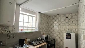 A compact kitchen with basic appliances, a window, and patterned wallpaper. - Casa Augusta 2 (Braga)