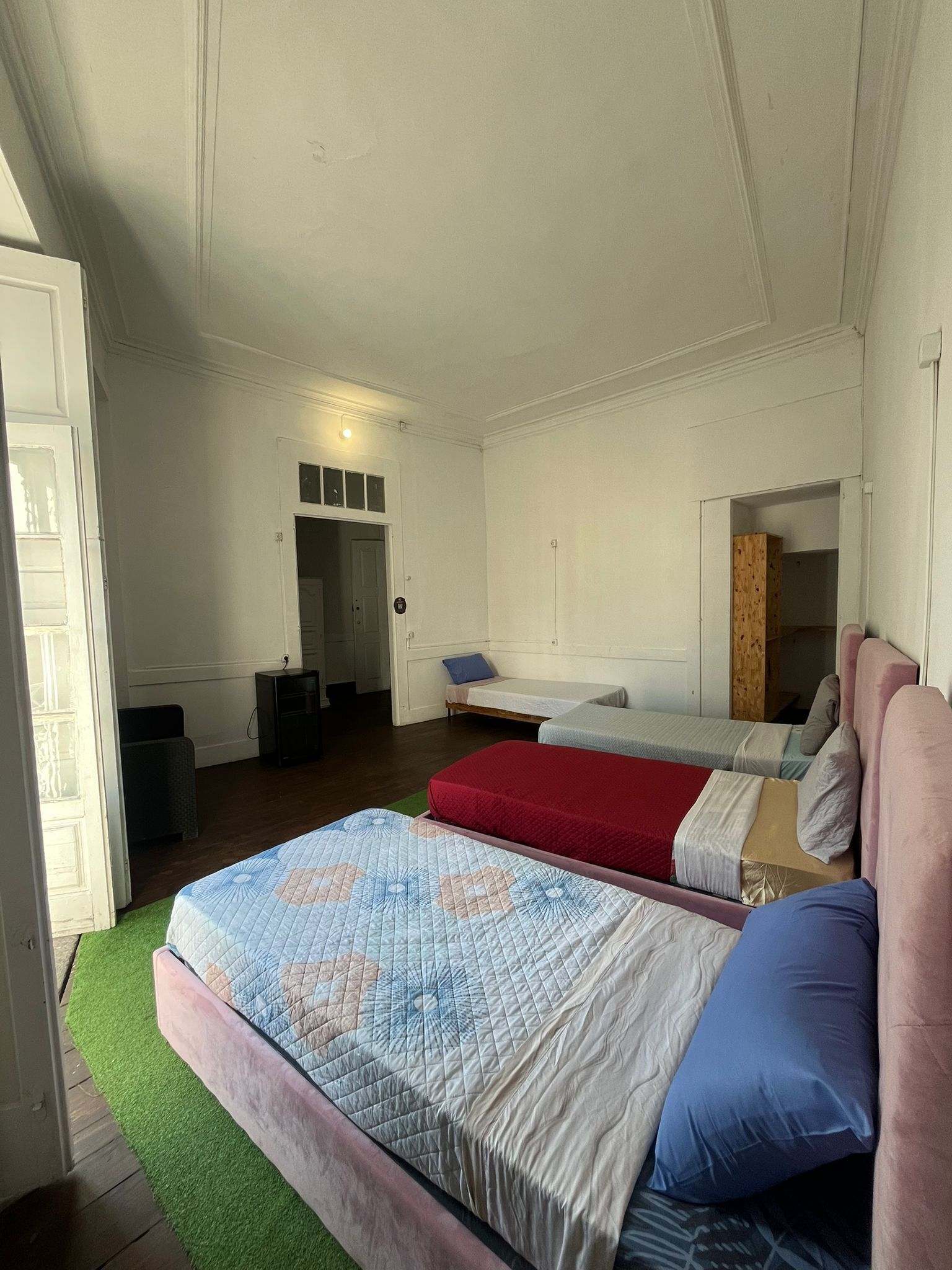 A bedroom with two beds, a door leading to a bathroom, and a small desk.