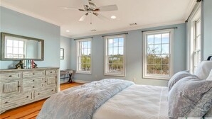 A bedroom with a large bed, a ceiling fan, and multiple windows. - Historic 3-Bed Townhouse w/ Courtyard & Parking (Savannah)