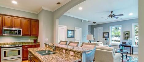 A spacious kitchen with granite countertops, wooden cabinets, and a built-in microwave.