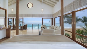 A spacious bedroom with a large bed, a sitting area with a view of the ocean, and a balcony with a railing. - The Lucky Elephant (Hikkaduwa)