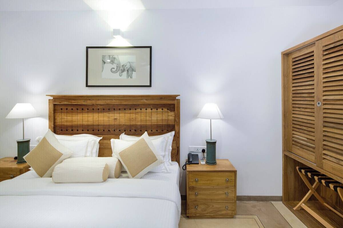 Ein ordentlich eingerichtetes Schlafzimmer mit einem Holzkopfteil, einem Nachttisch mit Lampe, einem gerahmten Bild an der Wand und einem Holzschrank.