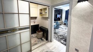 Een modern interieur met een keukenhoek, een eethoek met stoelen, en een televisietoestel.