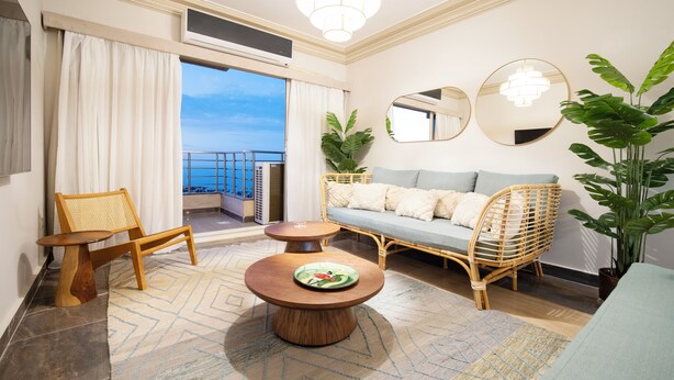 A modern living room with a sofa, chairs, a coffee table, and a large potted plant.