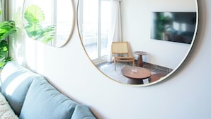 A modern living room with a sofa, two round mirrors, a chandelier, and a television on the wall.