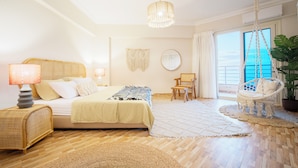 A bedroom with a bed, bedside lamps, a hanging chair, a large window with a view, and a ceiling light.