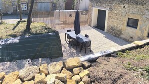 Een terras met een tafel en stoelen, een overdekte zithoek en een stenen muur.