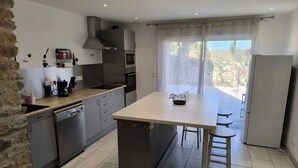 Een moderne keuken met grijze kastjes, een centraal eiland en een groot raam.