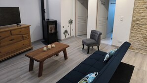 Een woonkamer met een bank, een houten salontafel, een televisie, een open haard en een accentmuur van steen.