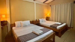 A hotel room with two single beds, wooden headboards, a ceiling fan, and a nightstand with a lamp. - LUMARA LODGE (Guayabo)