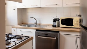 A compact kitchen with a gas stove, a dishwasher, a microwave, and a sink. - Casa Medea - One Bedroom Apartment, Sleeps 2 (Rome)
