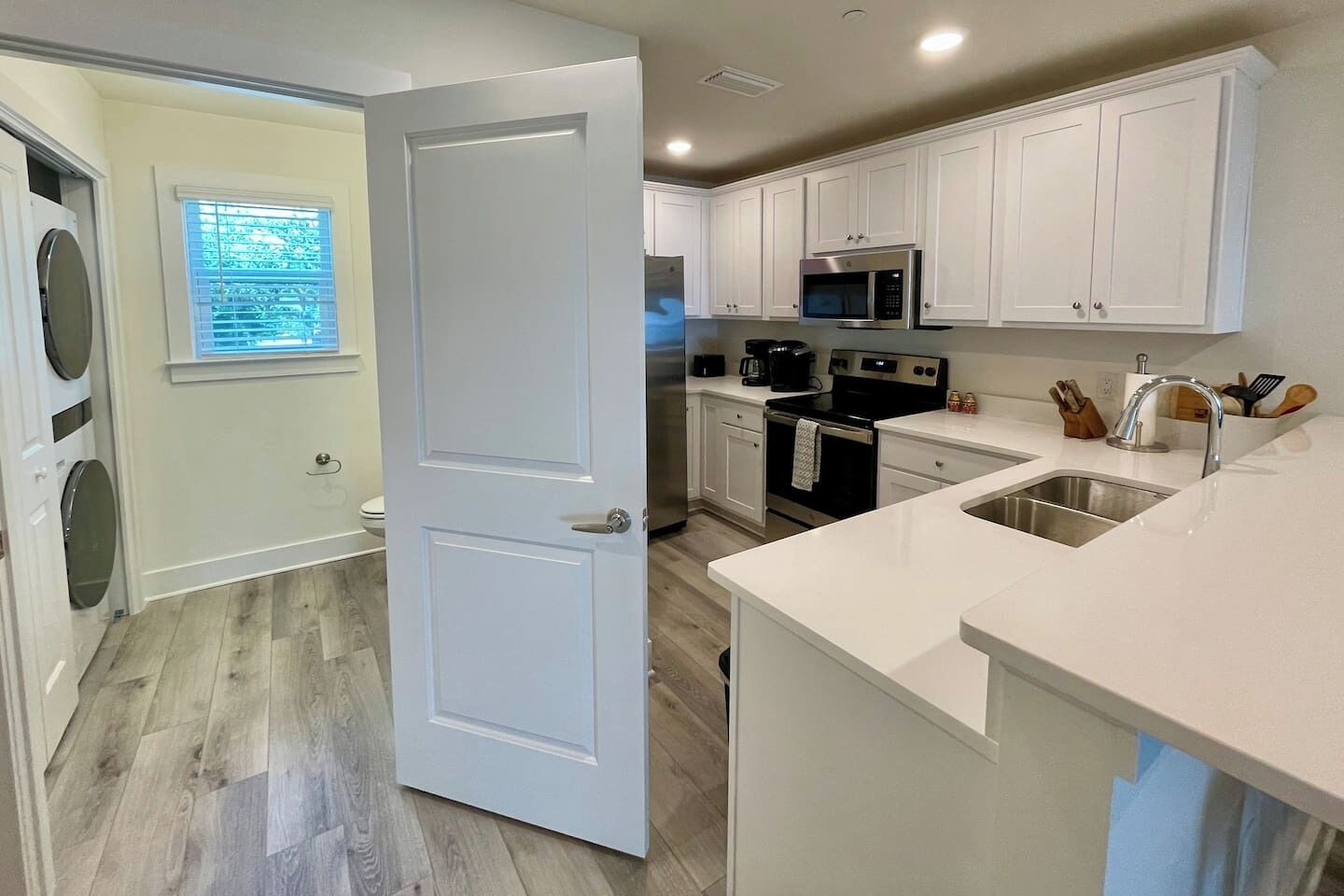 A modern kitchen with white cabinetry, a stainless steel sink, and a built-in microwave.