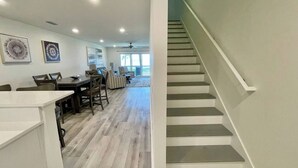 Un interior moderno con una escalera, comedor y obras de arte en las paredes.