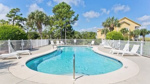 A swimming pool with a curved edge, surrounded by a white fence and white lounge chairs. - ChilSea: Kayak, SUP, Views & more! (Pensacola)