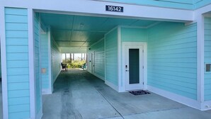 A corridor with teal walls and a concrete floor, leading to a door with a number sign above it. - ChilSea: Kayak, SUP, Views & more! (Pensacola)