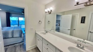 A modern bathroom with a double sink, a large mirror, and a view of a balcony. - Island Oasis: Beautiful Bay View, 2 Kayaks & Pool! (Pensacola)