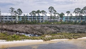A coastal hotel with multiple-story buildings, a beachfront, and a marshy area with tall grasses. - Island Oasis: Beautiful Bay View, 2 Kayaks & Pool! (Pensacola)