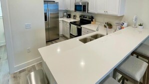 A modern kitchen with white cabinets, stainless steel appliances, and a central island with bar stools.