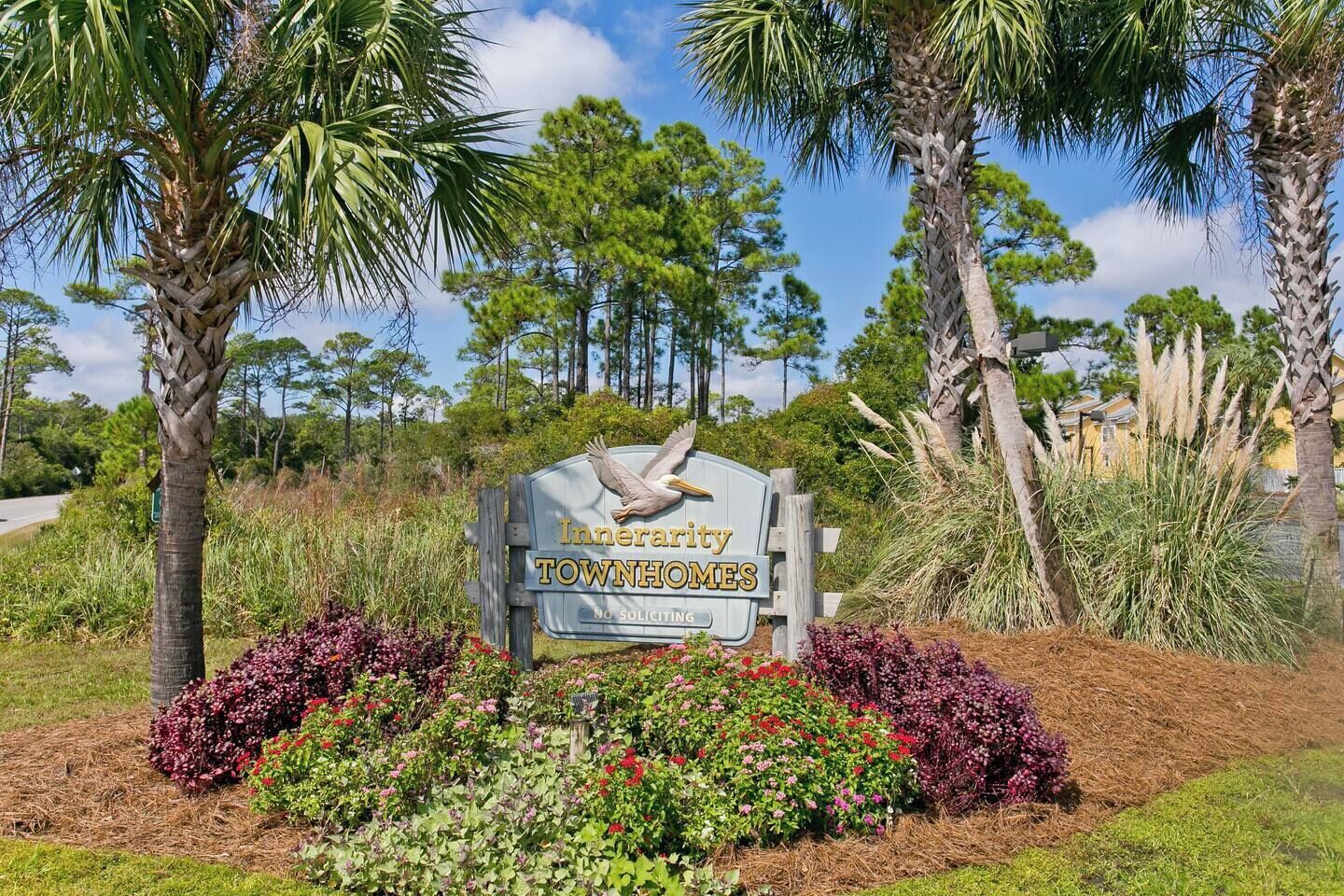 A sign for Innerview Townhomes with a no soliciting notice, surrounded by landscaped gardens and palm trees.