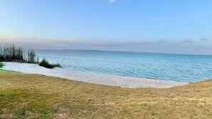 A beach with a clear sky and calm sea. - Tranquil Seas: Waterfront Unit with Kayaks & More! (Pensacola)